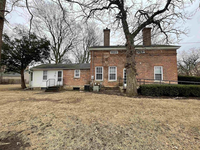 rear view of house with a yard, a chimney, fence, and brick siding