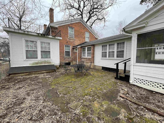 rear view of house featuring brick siding and a chimney