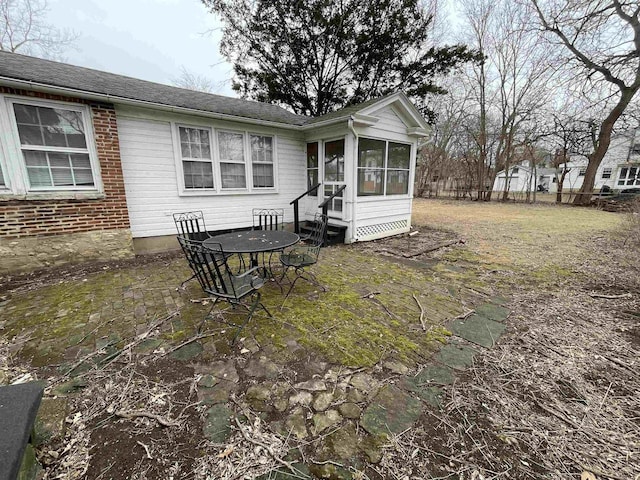 back of house featuring entry steps, brick siding, and a sunroom