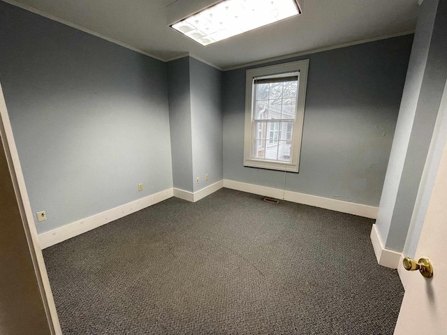 empty room with ornamental molding, dark carpet, visible vents, and baseboards