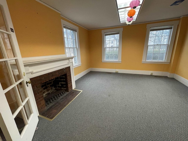 unfurnished living room featuring carpet floors, crown molding, visible vents, a brick fireplace, and baseboards