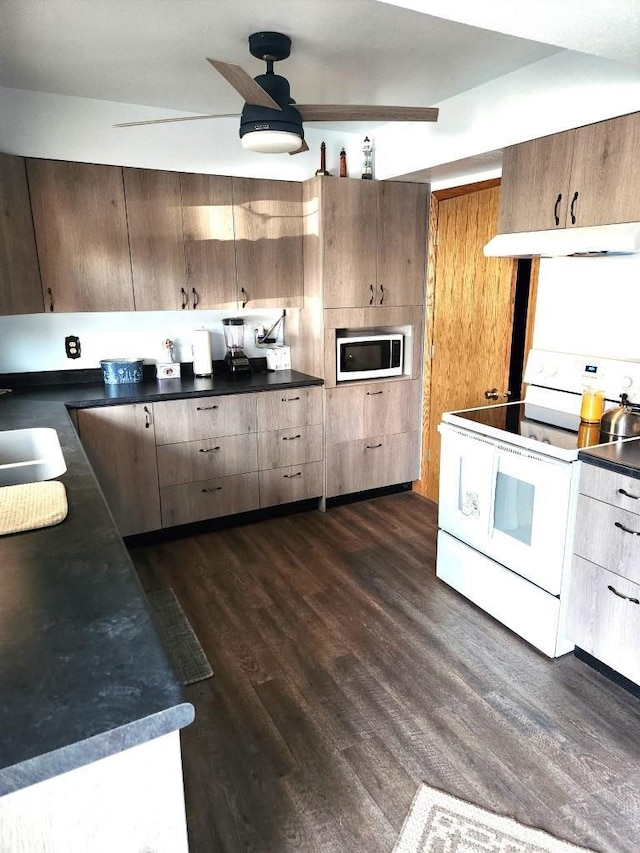 kitchen with dark wood-style floors, dark countertops, white range with electric stovetop, and under cabinet range hood