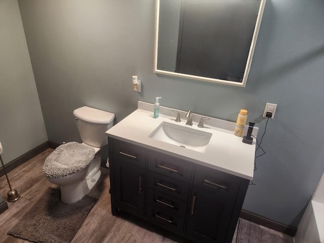 bathroom with baseboards, vanity, toilet, and wood finished floors