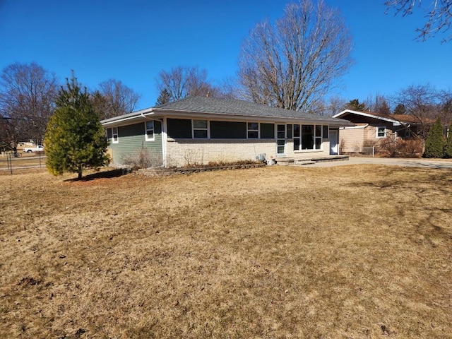 rear view of property featuring brick siding and a lawn