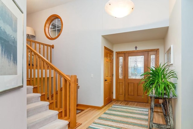 foyer entrance with stairway, wood finished floors, and baseboards