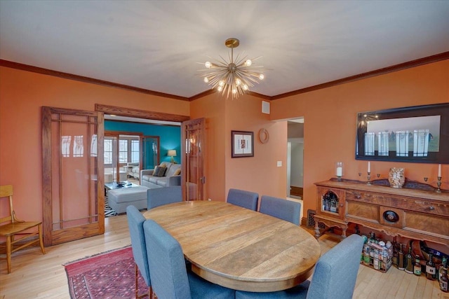 dining area featuring crown molding, light wood-style floors, visible vents, and a notable chandelier