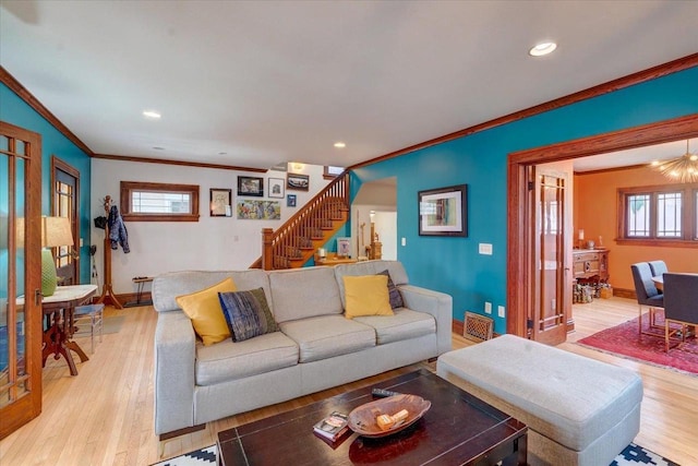 living area featuring crown molding, light wood-style flooring, and stairs