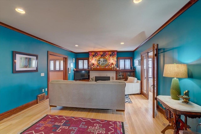 living room featuring light wood-style floors, a fireplace, visible vents, and ornamental molding