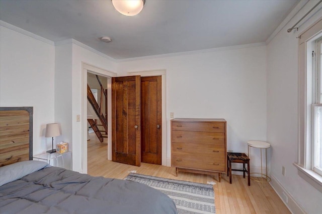 bedroom with baseboards, ornamental molding, and wood finished floors