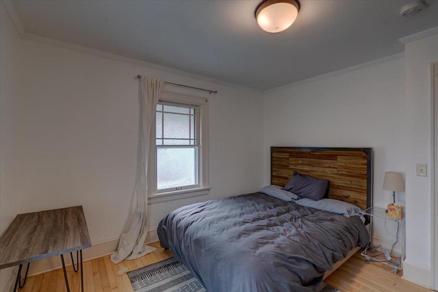 bedroom featuring hardwood / wood-style flooring, baseboards, and crown molding