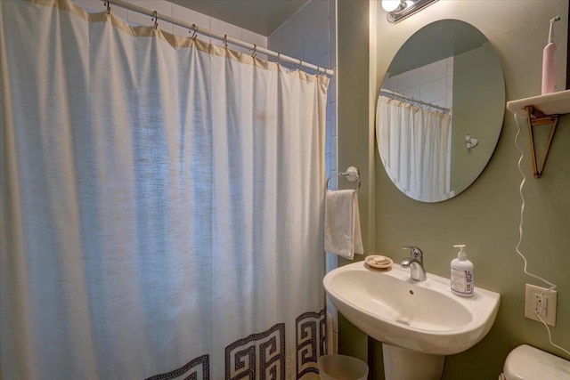 bathroom featuring a sink, toilet, and a shower with curtain