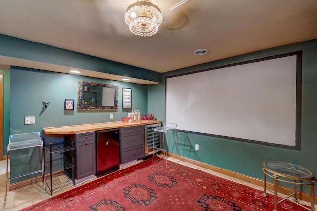 interior space with a dry bar, beverage cooler, visible vents, baseboards, and an inviting chandelier