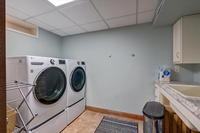 washroom with separate washer and dryer, a sink, cabinet space, and baseboards