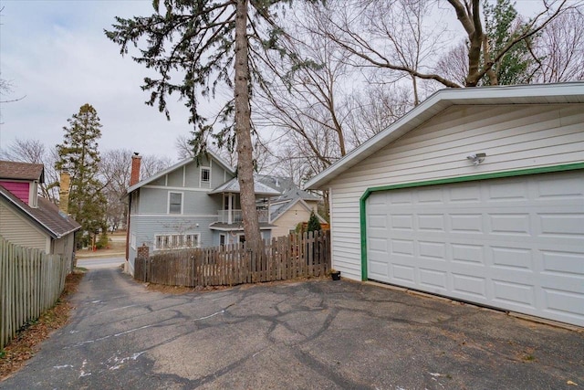 garage featuring aphalt driveway and fence