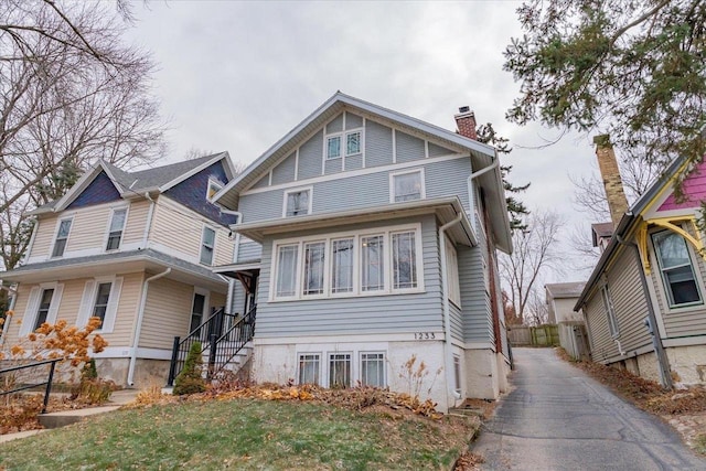 view of front of home featuring aphalt driveway, a chimney, and fence