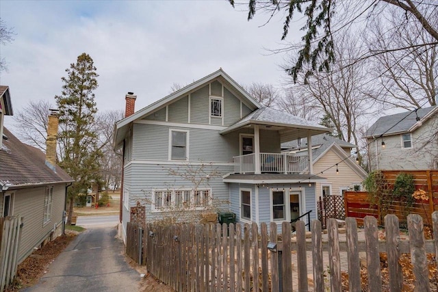 view of front facade with a balcony and a fenced front yard