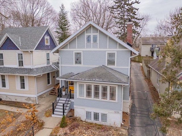 view of front of home with a shingled roof and a chimney