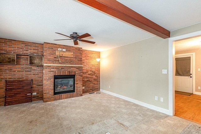 unfurnished living room with a textured ceiling, beamed ceiling, a fireplace, and carpet flooring