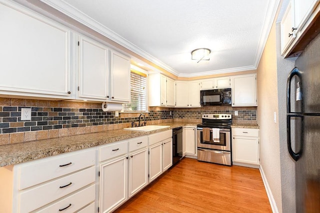 kitchen with backsplash, ornamental molding, a sink, light wood-type flooring, and black appliances