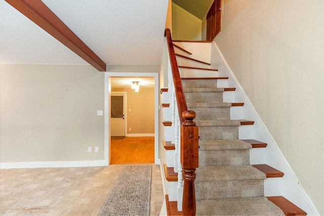 staircase with carpet, beam ceiling, and baseboards