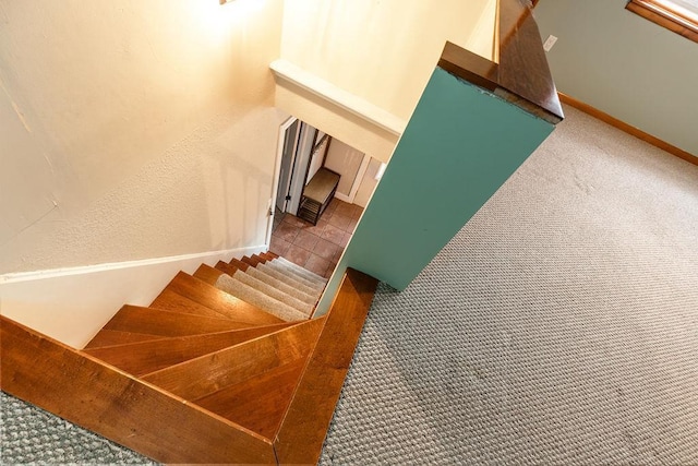 staircase with a textured wall, carpet floors, tile patterned flooring, and baseboards