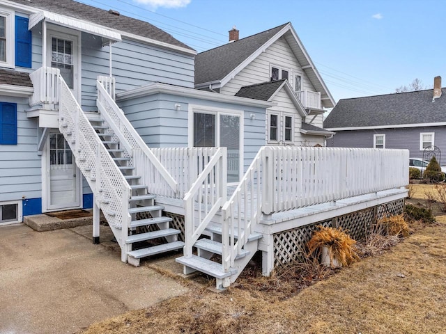 back of property featuring a shingled roof, a wooden deck, and stairs