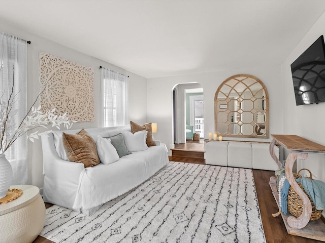 living room with arched walkways and wood finished floors