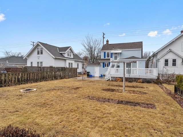 back of property with a deck, a chimney, fence, and a lawn