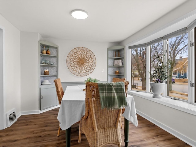 dining space featuring dark wood-type flooring, visible vents, and baseboards