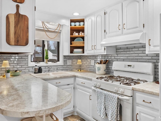 kitchen with white gas stove, ventilation hood, a sink, and white cabinetry