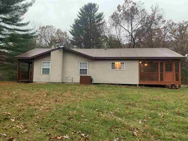 back of house with a sunroom and a lawn