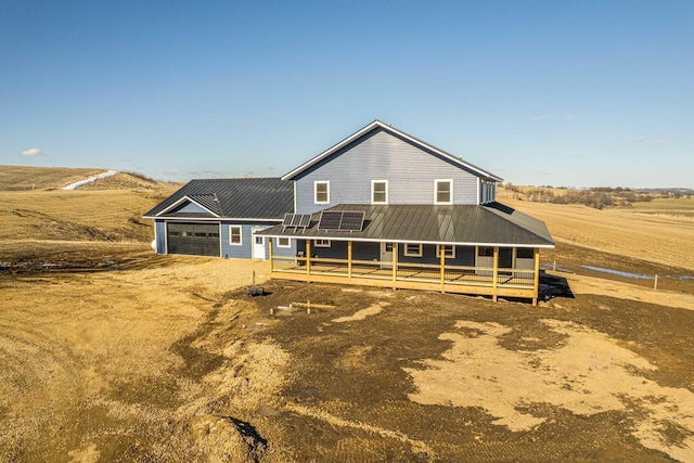 view of front facade featuring dirt driveway, metal roof, and an attached garage