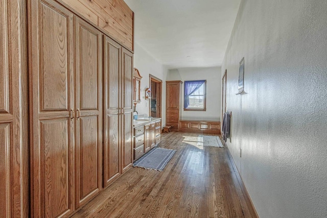 corridor featuring a textured wall, a sink, and wood finished floors