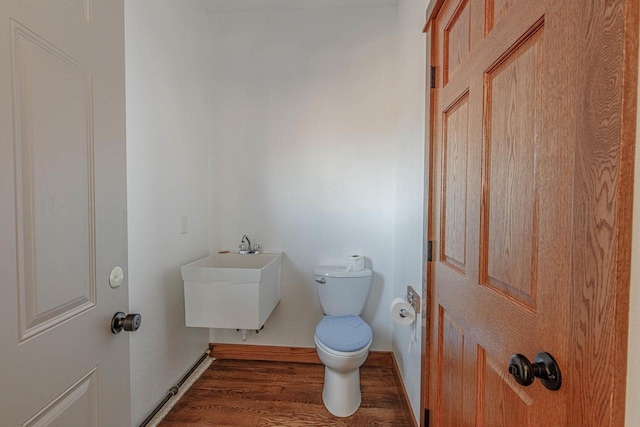 bathroom featuring baseboards, a sink, toilet, and wood finished floors