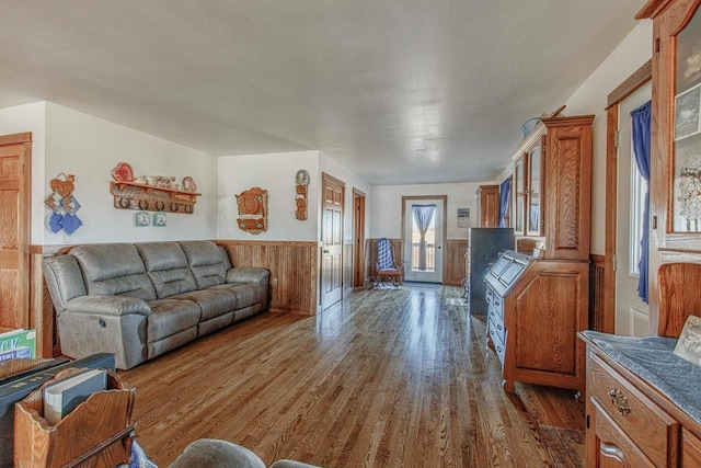 living room featuring a wainscoted wall and dark wood finished floors