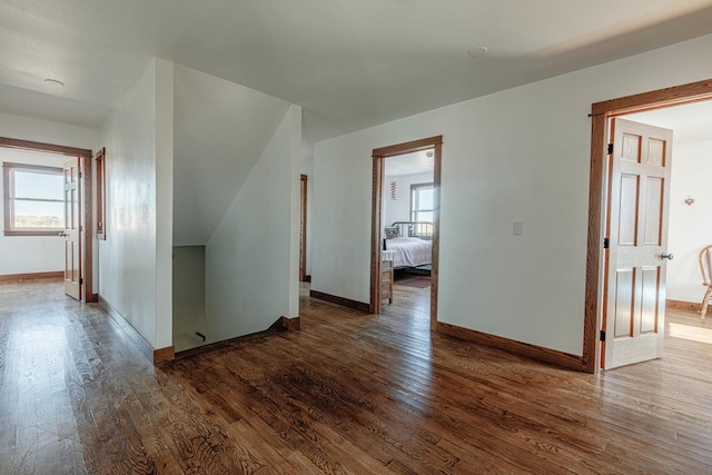 hall with wood finished floors, a wealth of natural light, and baseboards