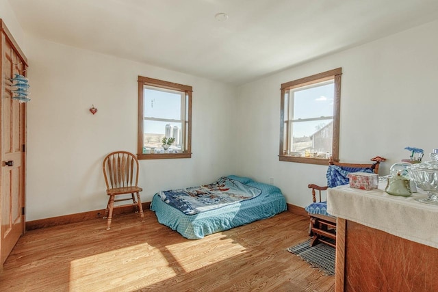 bedroom featuring light wood-type flooring, multiple windows, and baseboards