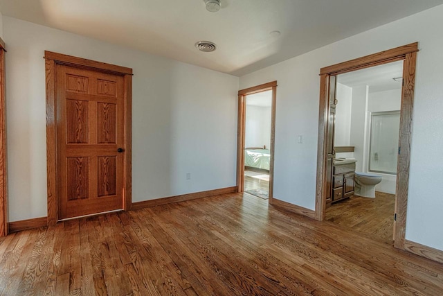 unfurnished bedroom featuring baseboards, visible vents, and wood finished floors