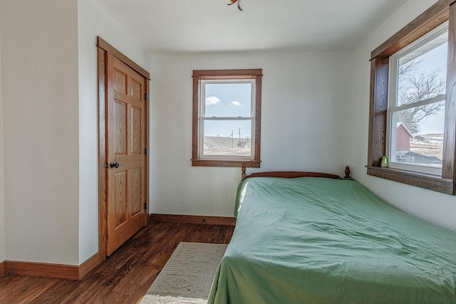 bedroom with multiple windows, baseboards, and dark wood finished floors