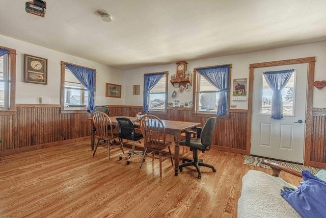 dining area with light wood-type flooring, wainscoting, and wood walls