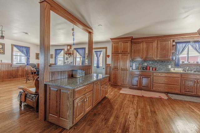 kitchen with a wainscoted wall, wood finished floors, and brown cabinets