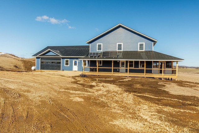 farmhouse with dirt driveway, covered porch, and an attached garage