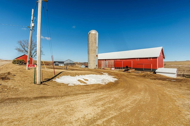 view of yard with a garage, an outbuilding, and dirt driveway