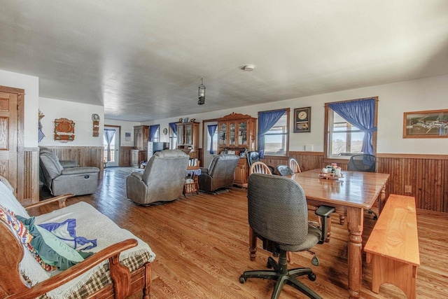 interior space with light wood finished floors, wood walls, and wainscoting