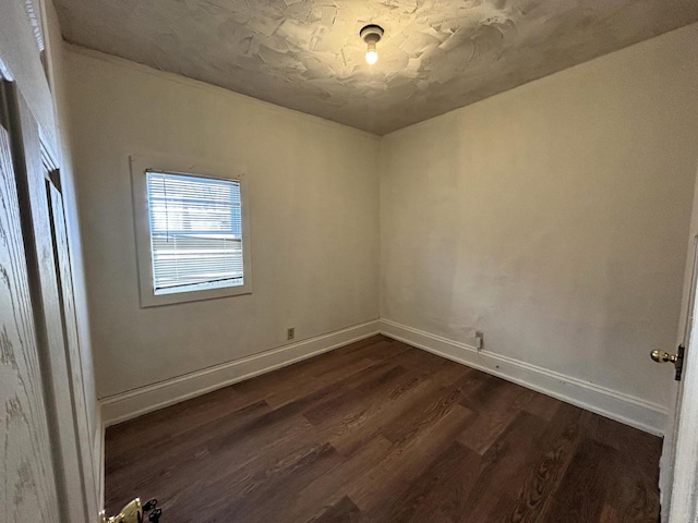 spare room featuring dark wood-style floors and baseboards