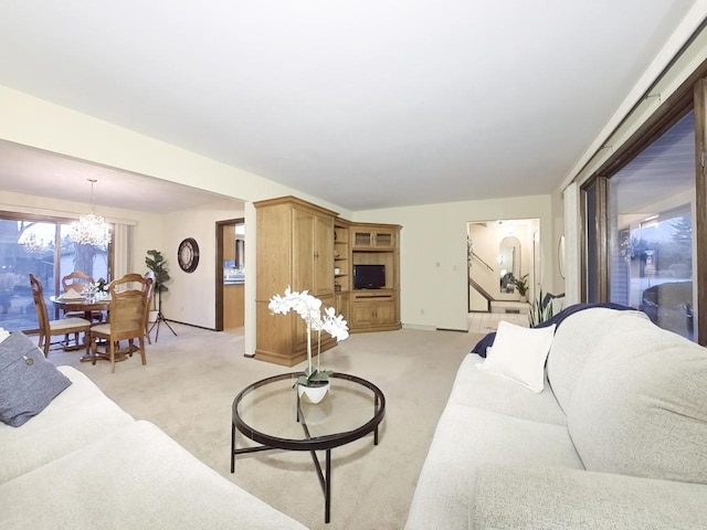 living area with an inviting chandelier and light colored carpet