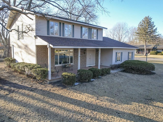 view of front of property with a porch, brick siding, and roof with shingles