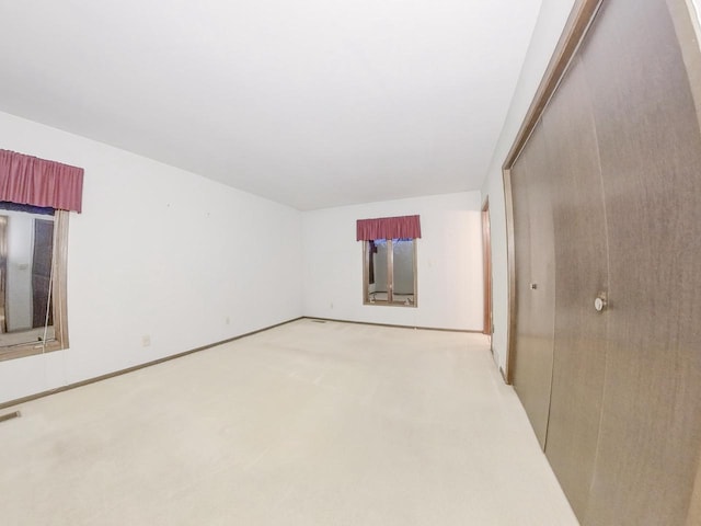 spare room with light carpet and baseboards