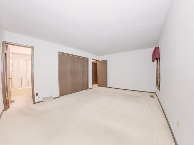 bedroom with connected bathroom, visible vents, a closet, and light colored carpet