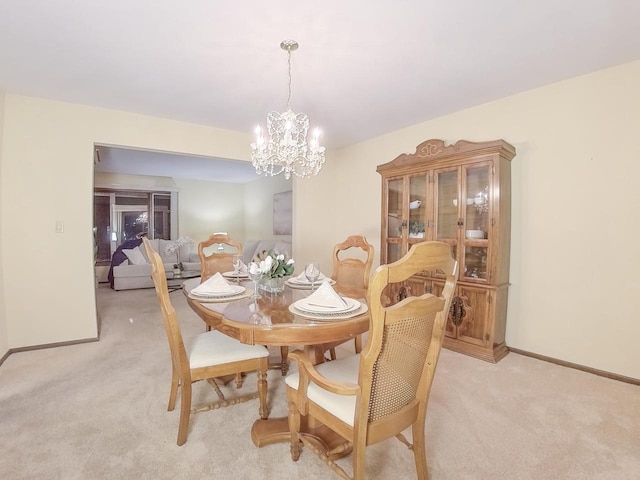 dining space with baseboards, a notable chandelier, and light colored carpet